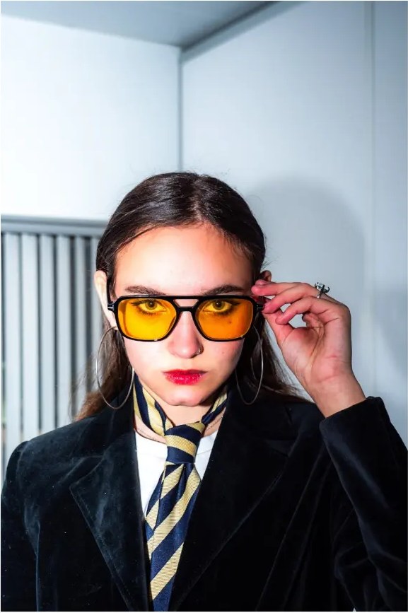 Portrait of Vita Davydova wearing yellow sunglasses and a striped tie